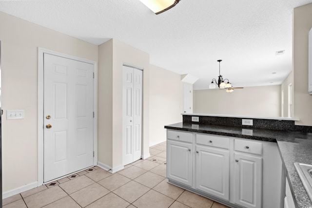 kitchen with an inviting chandelier, white cabinets, light tile patterned floors, a textured ceiling, and decorative light fixtures