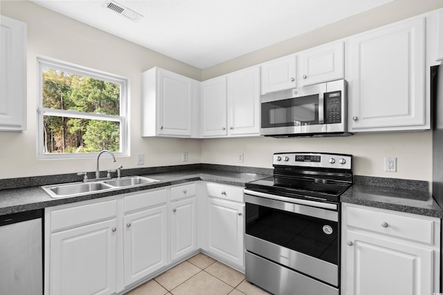 kitchen with white cabinets, light tile patterned floors, sink, and appliances with stainless steel finishes