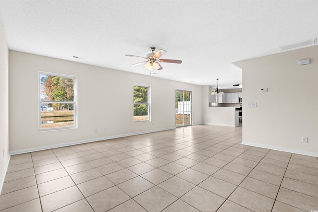 empty room with a wealth of natural light, light tile patterned flooring, and a textured ceiling