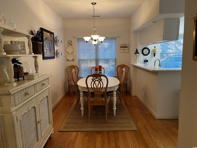 dining area with light hardwood / wood-style floors, a notable chandelier, and sink