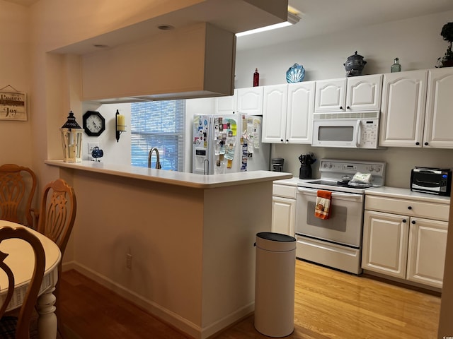 kitchen with white cabinets, light wood-type flooring, white appliances, and kitchen peninsula