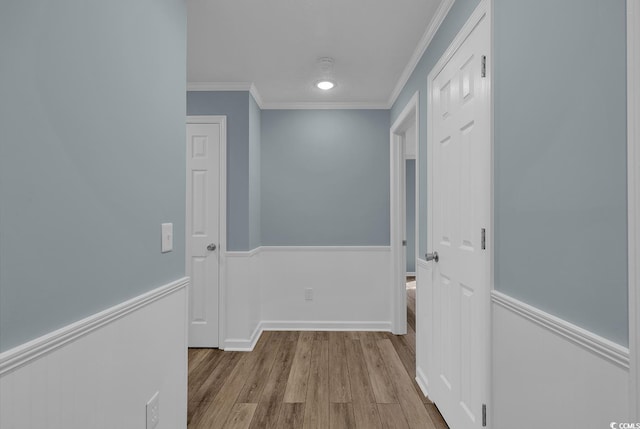 corridor with light hardwood / wood-style flooring and ornamental molding