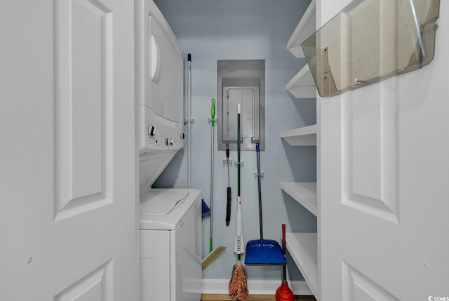 laundry room with wood-type flooring, stacked washer and dryer, and electric panel