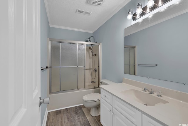 full bathroom featuring shower / bath combination with glass door, hardwood / wood-style flooring, toilet, ornamental molding, and a textured ceiling