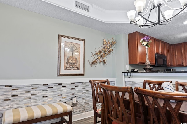 dining area with wood-type flooring, crown molding, a textured ceiling, and a chandelier