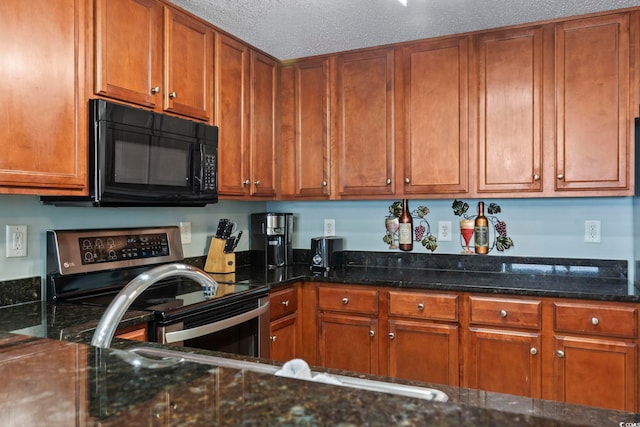 kitchen with stainless steel range with electric cooktop, dark stone counters, and a textured ceiling