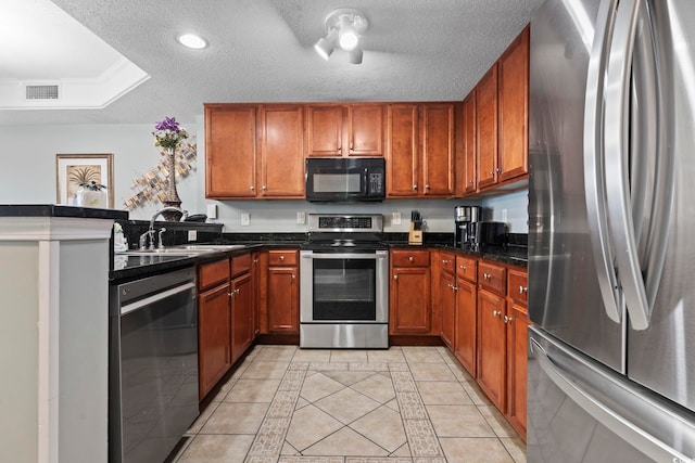 kitchen with light tile patterned floors, sink, a textured ceiling, and appliances with stainless steel finishes