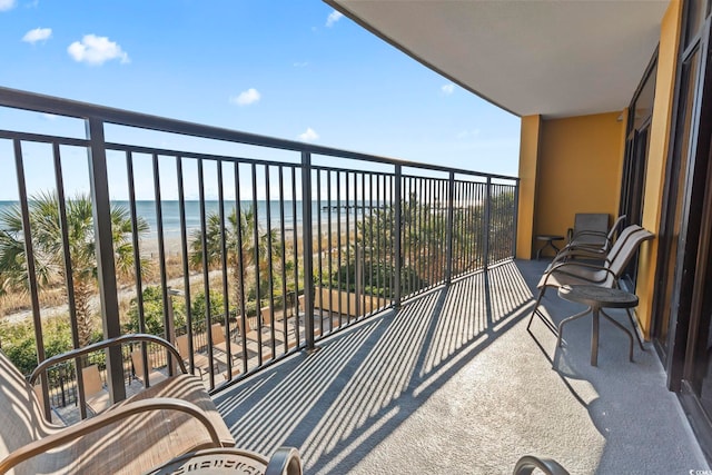 balcony with a water view and a view of the beach