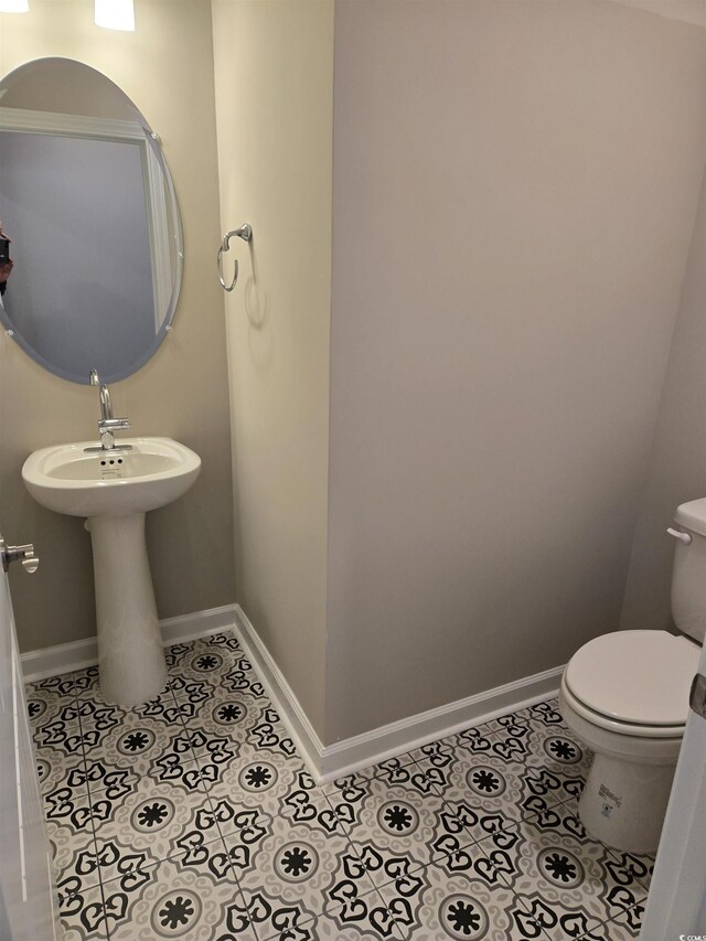 half bathroom featuring toilet, baseboards, and tile patterned floors