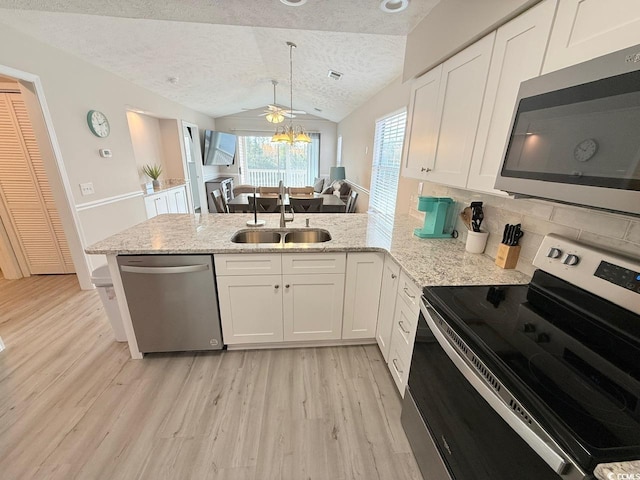 kitchen featuring vaulted ceiling, appliances with stainless steel finishes, kitchen peninsula, and sink