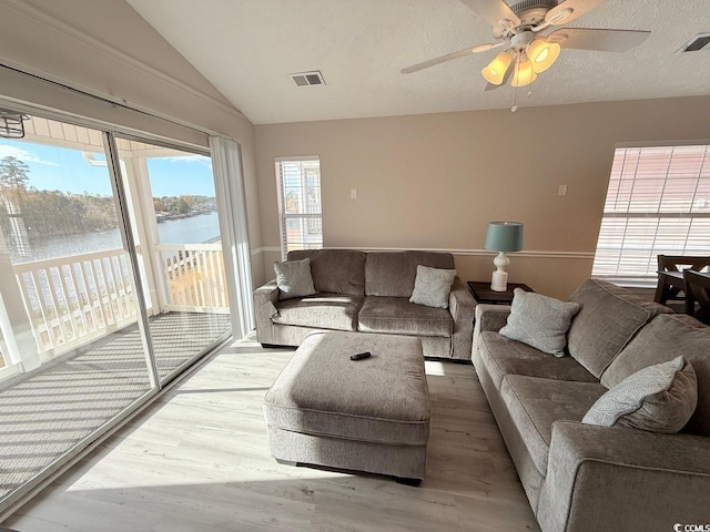 living room featuring hardwood / wood-style flooring, vaulted ceiling, a water view, and ceiling fan