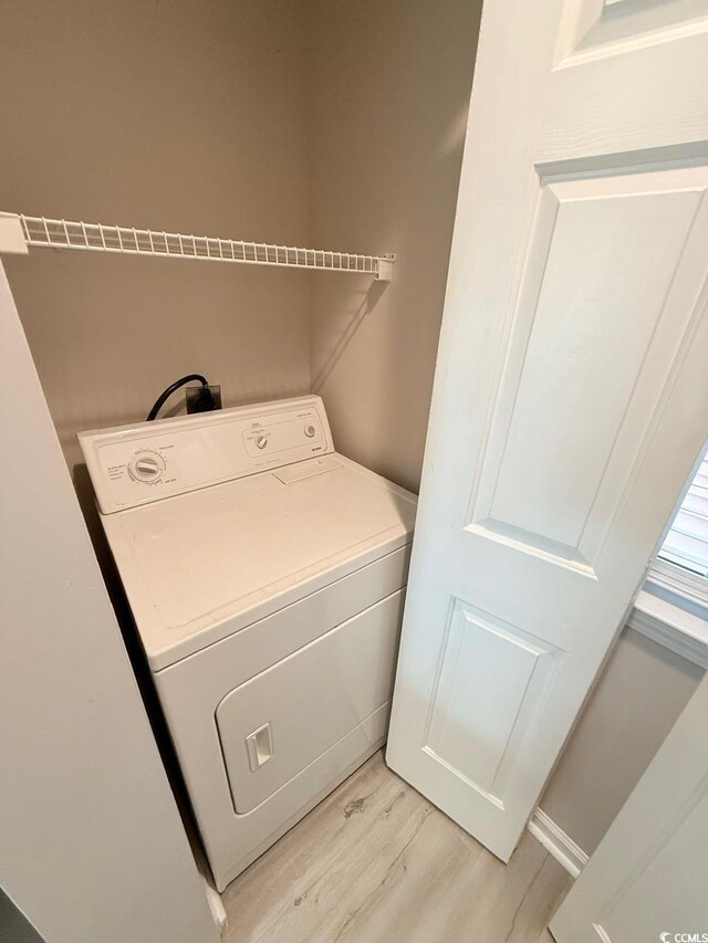 clothes washing area featuring washer / clothes dryer and light hardwood / wood-style flooring