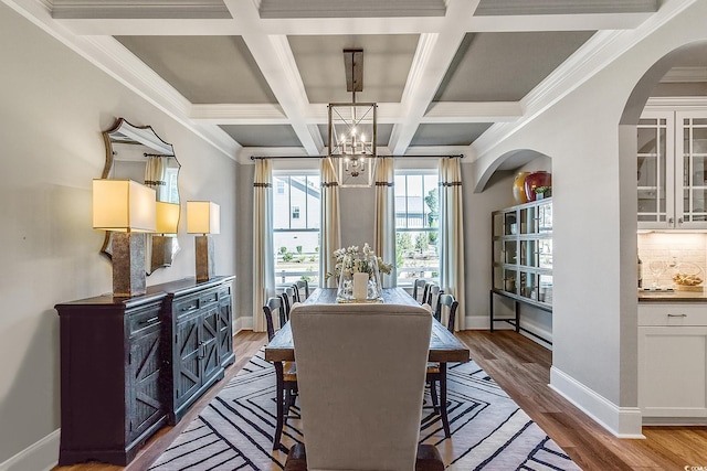 dining room with coffered ceiling, crown molding, beamed ceiling, a notable chandelier, and light hardwood / wood-style floors