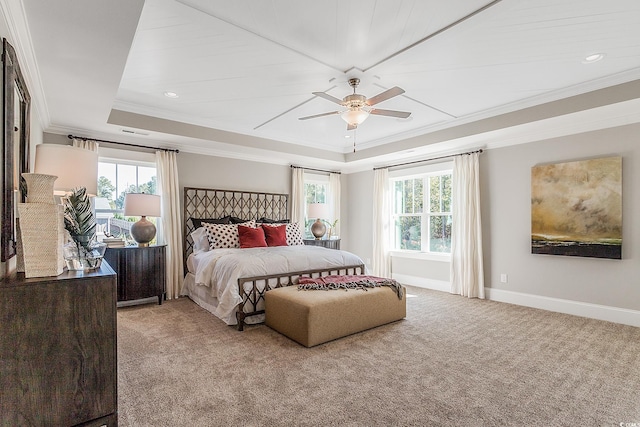 carpeted bedroom with a tray ceiling, multiple windows, ceiling fan, and ornamental molding