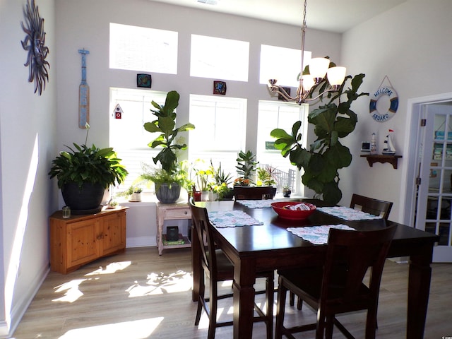 dining area with light wood-style floors and an inviting chandelier