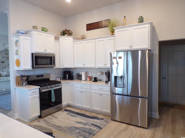 kitchen featuring white cabinets, appliances with stainless steel finishes, decorative backsplash, and light countertops