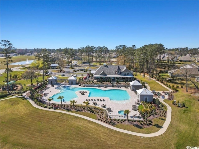 community pool featuring a water view, a patio area, fence, and a yard