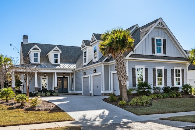 6105 Bolsena Pl, Myrtle Beach, SC 29577 - view of front facade with driveway, french doors, board and batten siding, a chimney, and covered porch