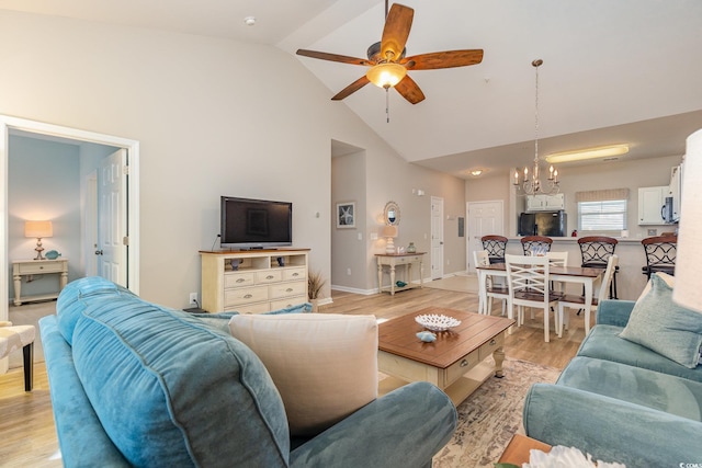 living room with ceiling fan with notable chandelier, high vaulted ceiling, and light hardwood / wood-style floors