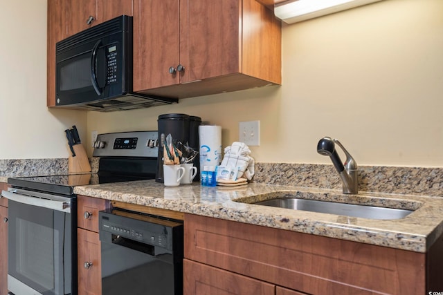 kitchen with light stone countertops, sink, and black appliances