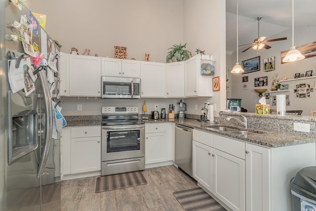 kitchen featuring white cabinets, sink, dark stone countertops, kitchen peninsula, and stainless steel appliances