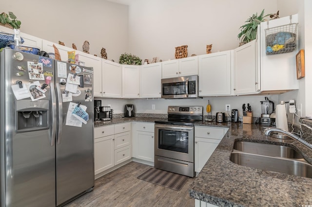 kitchen with white cabinetry, sink, dark hardwood / wood-style flooring, dark stone countertops, and appliances with stainless steel finishes