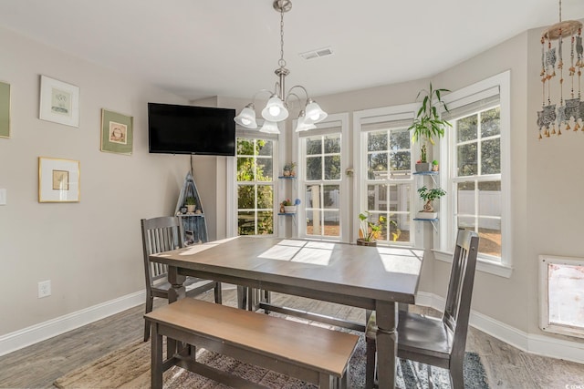 dining space featuring hardwood / wood-style flooring and an inviting chandelier