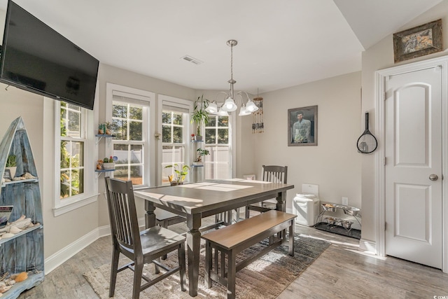 dining space with a chandelier, light wood-type flooring, and a healthy amount of sunlight