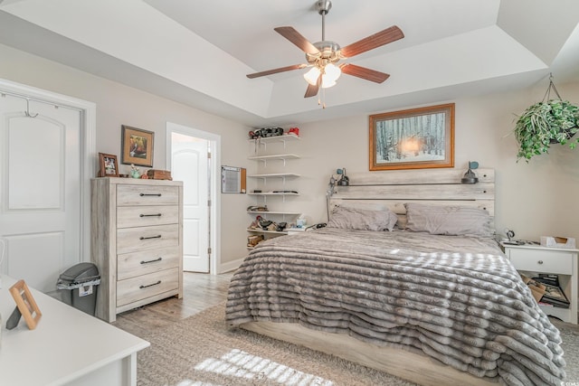 bedroom with a tray ceiling, ceiling fan, and light hardwood / wood-style floors