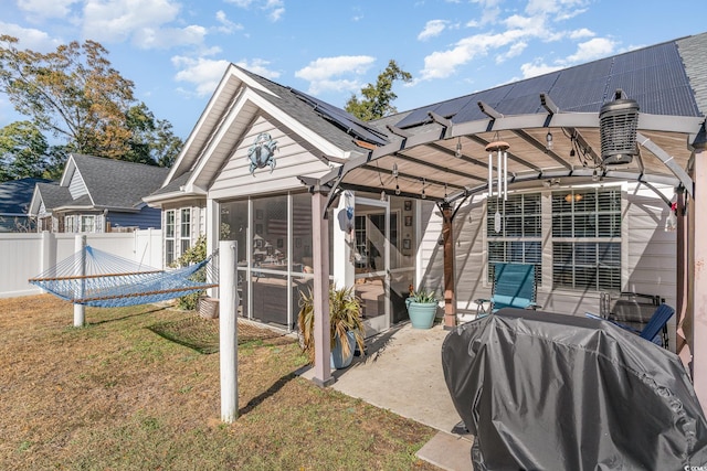 rear view of property with solar panels, a pergola, a lawn, and a sunroom