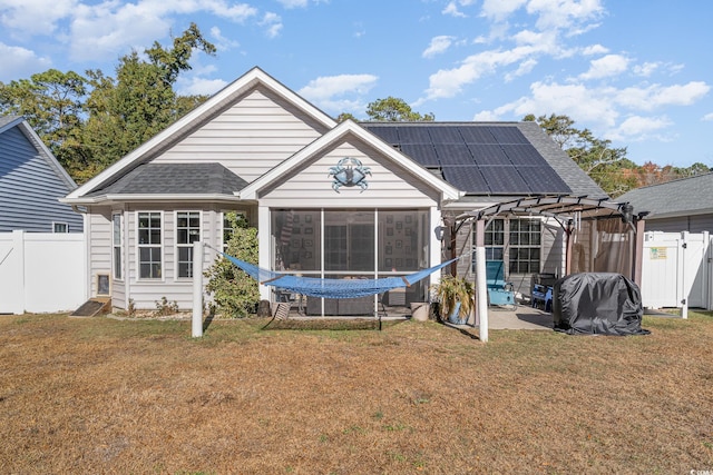 back of property featuring solar panels, a patio, a lawn, and a sunroom