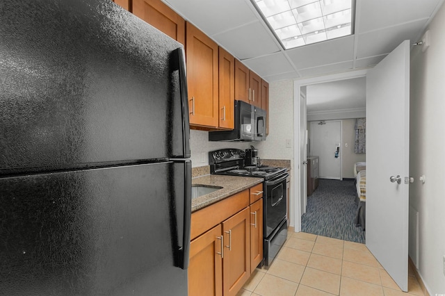 kitchen with stone counters, light tile patterned flooring, and black appliances