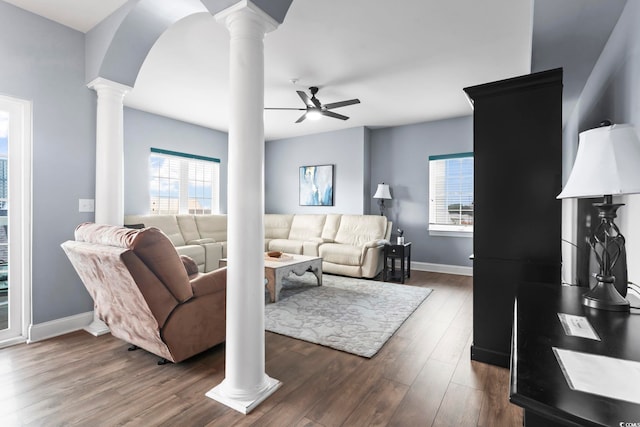 living room with decorative columns, ceiling fan, and dark wood-type flooring