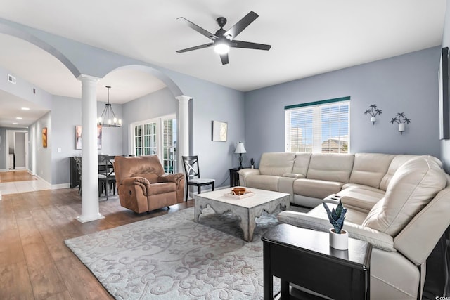 living room featuring hardwood / wood-style floors, ceiling fan with notable chandelier, and decorative columns