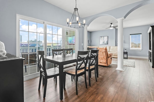 dining space with ceiling fan with notable chandelier, dark hardwood / wood-style floors, ornate columns, and plenty of natural light