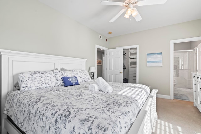 carpeted bedroom with a closet, a spacious closet, ensuite bath, and ceiling fan