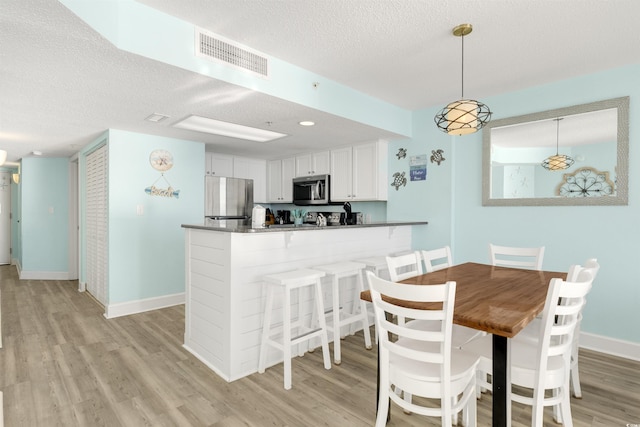 dining area featuring a textured ceiling and light wood-type flooring