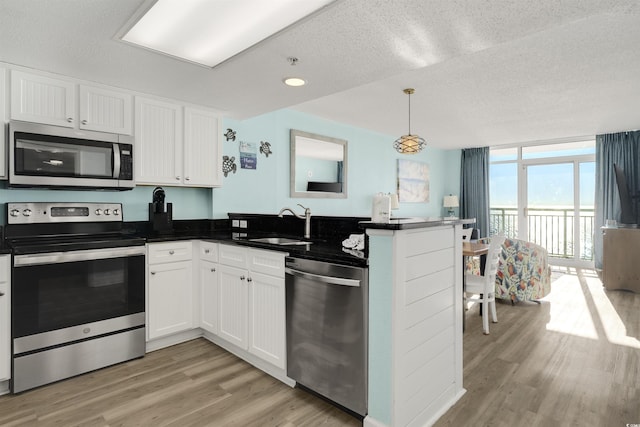 kitchen featuring decorative light fixtures, white cabinetry, stainless steel appliances, and kitchen peninsula