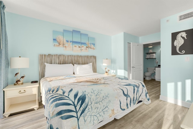 bedroom with ensuite bathroom and light hardwood / wood-style floors