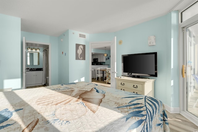 bedroom featuring ensuite bathroom and light hardwood / wood-style flooring