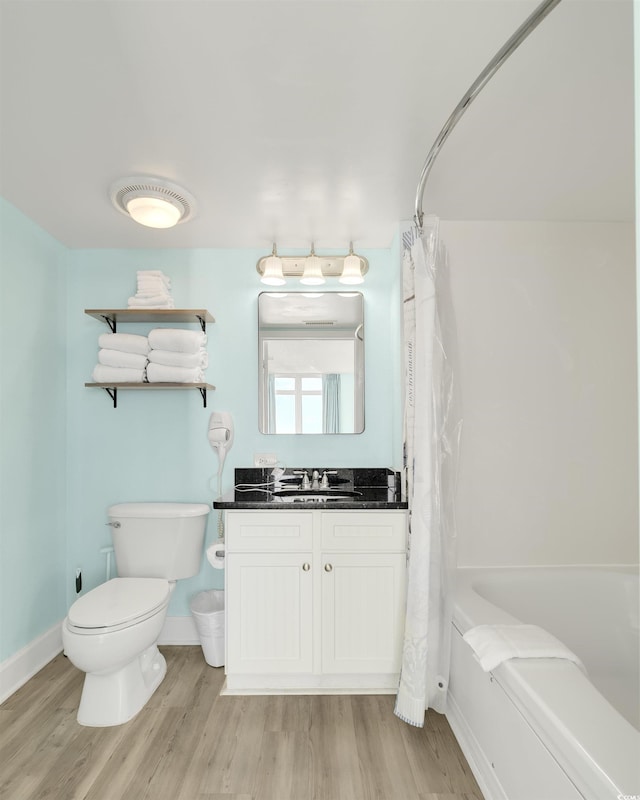 full bathroom with toilet, vanity, hardwood / wood-style flooring, and shower / tub combo with curtain