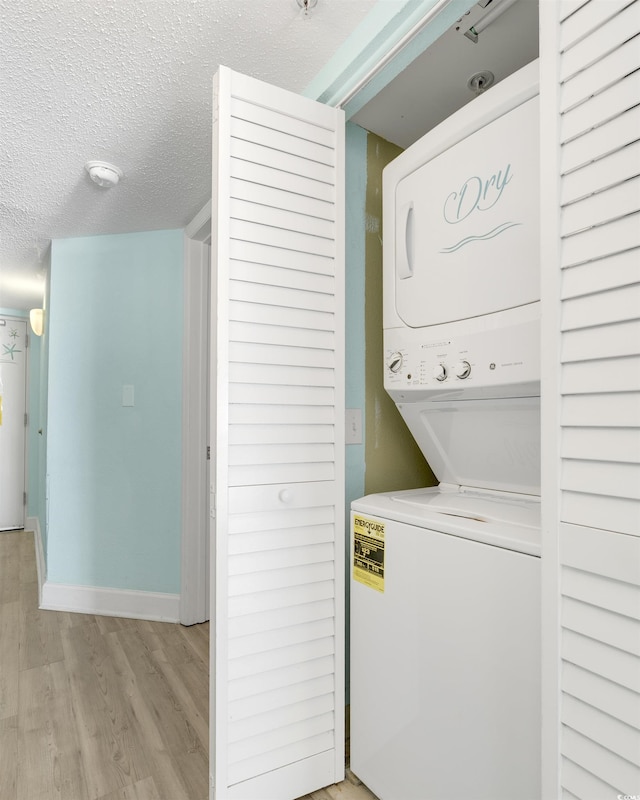 laundry area with stacked washing maching and dryer, a textured ceiling, and light hardwood / wood-style flooring