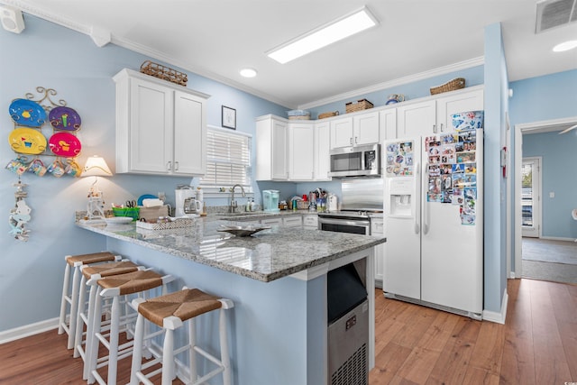 kitchen featuring white fridge with ice dispenser, white cabinets, ornamental molding, kitchen peninsula, and light stone counters