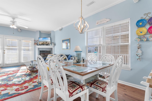 dining room with crown molding, ceiling fan with notable chandelier, and wood-type flooring