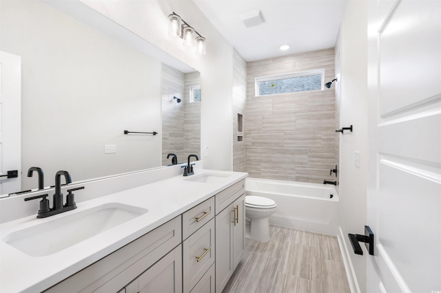 full bathroom featuring vanity, tiled shower / bath combo, and toilet