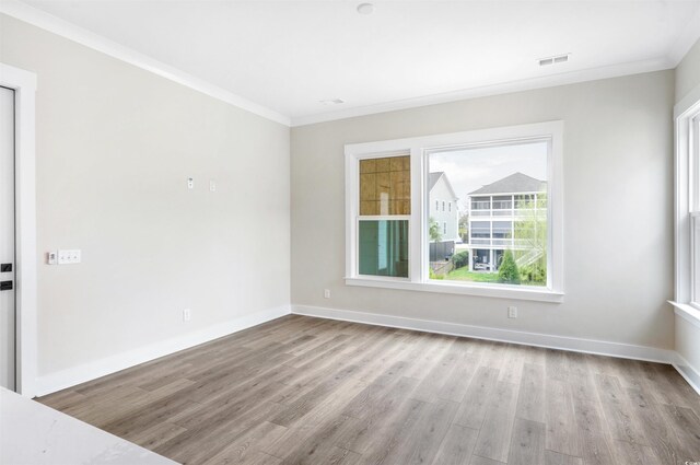 empty room with crown molding and light wood-type flooring