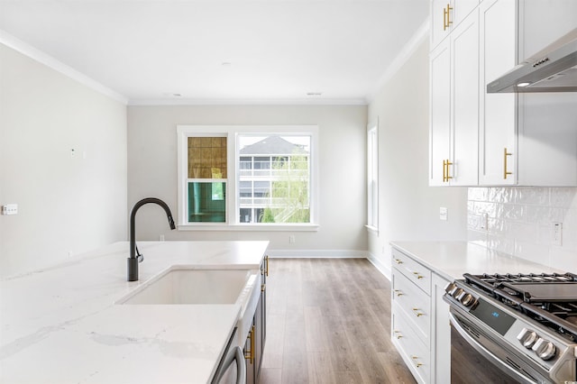 kitchen featuring sink, stainless steel gas range oven, white cabinetry, light stone countertops, and backsplash