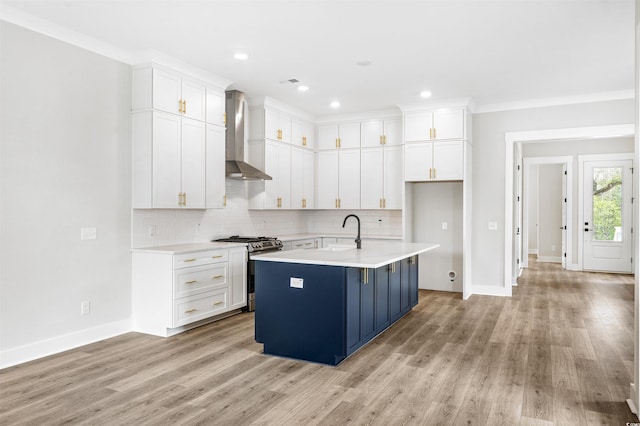 kitchen featuring white cabinetry, sink, a kitchen island with sink, gas stove, and wall chimney exhaust hood