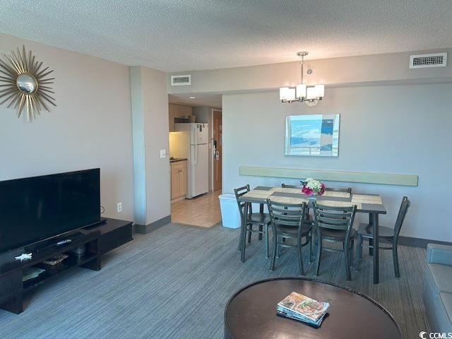 dining area featuring carpet, a textured ceiling, and a chandelier