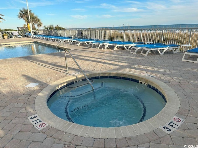 view of swimming pool with a community hot tub and a water view